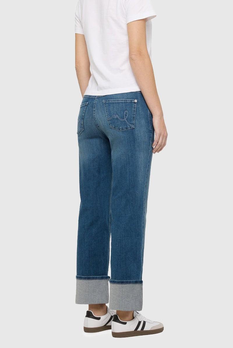 Person wearing blue jeans and a white shirt on a plain background