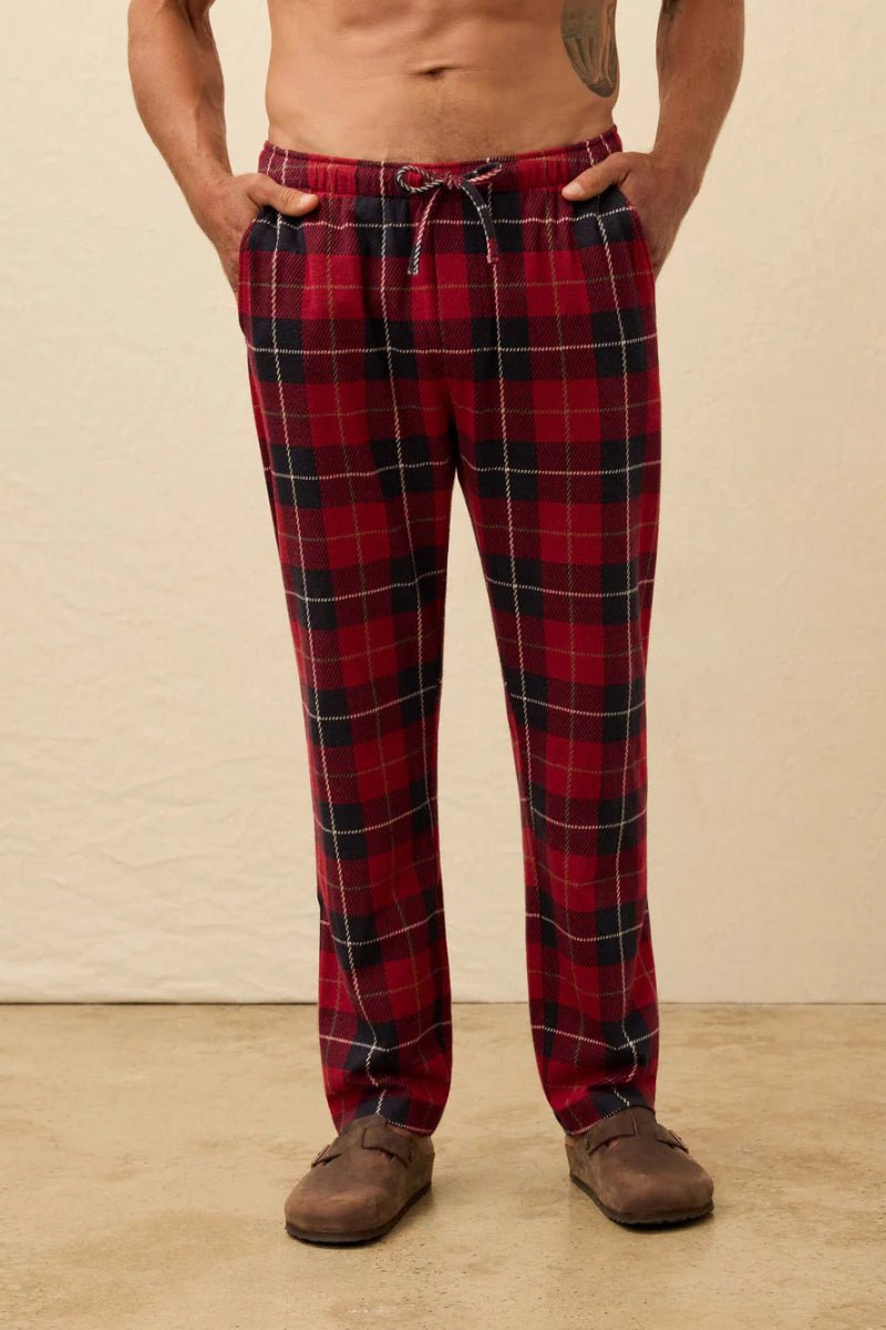Person wearing red plaid pajama pants on a beige background