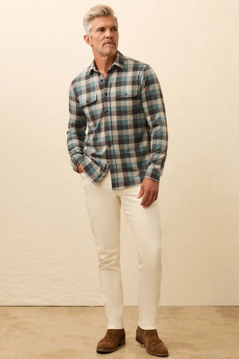 Man wearing a plaid shirt and white pants against a beige background