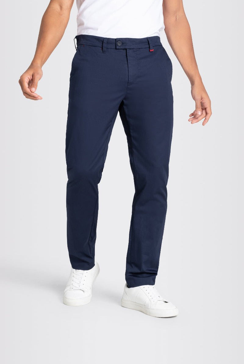 Person wearing navy pants and white shoes on a light gray background