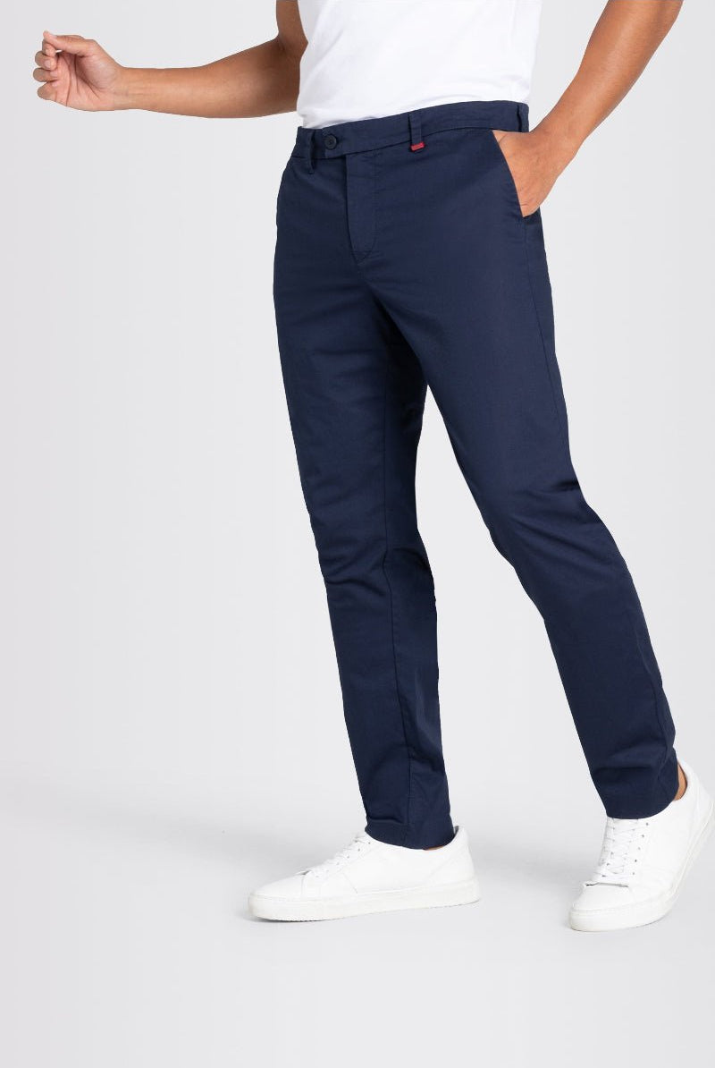 Person wearing navy pants and white shoes on a light gray background