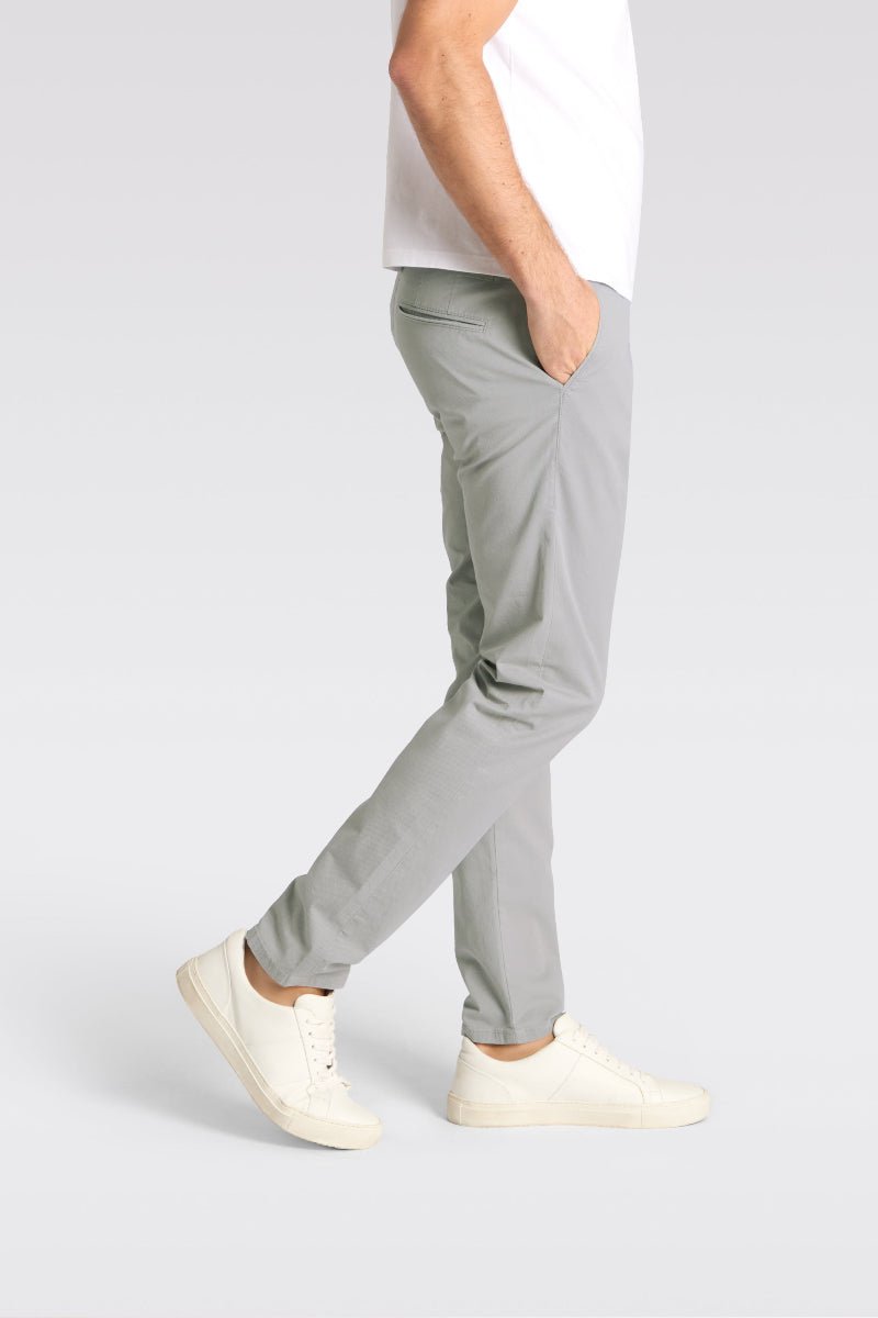 Person wearing light gray pants and white shoes on a plain background