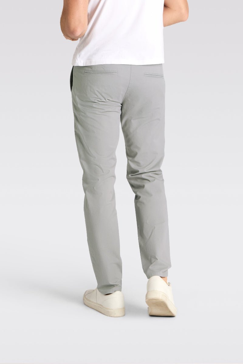 Person wearing light gray pants on a plain background