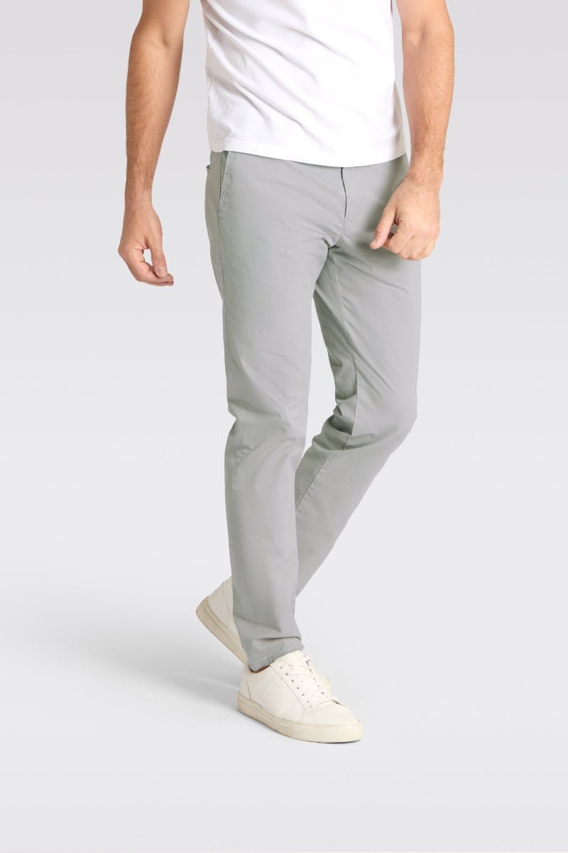 Person wearing light gray pants and white shoes on a plain background