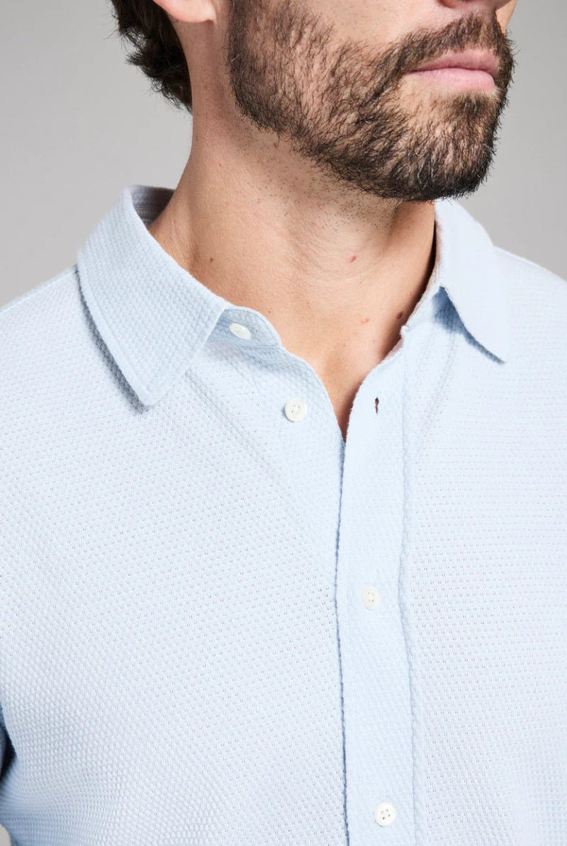 Light blue textured shirt worn by a person with a neutral background