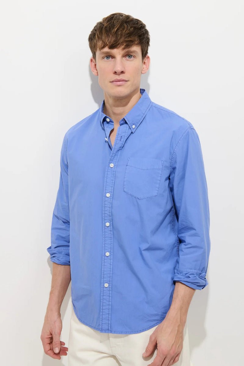 Man wearing a blue button-up shirt against a white background