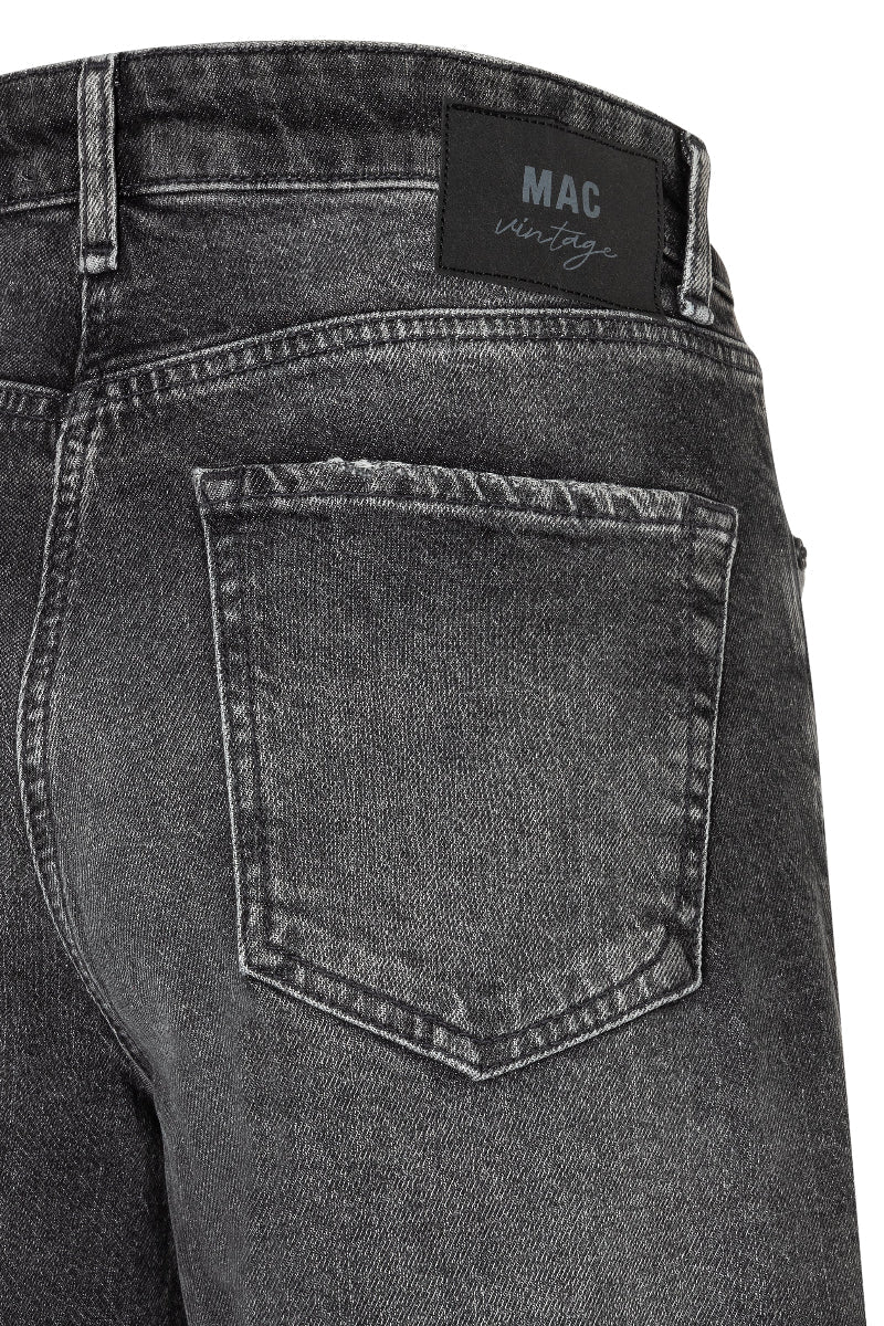 Close-up of a pair of gray jeans with a visible MAC label on a white background