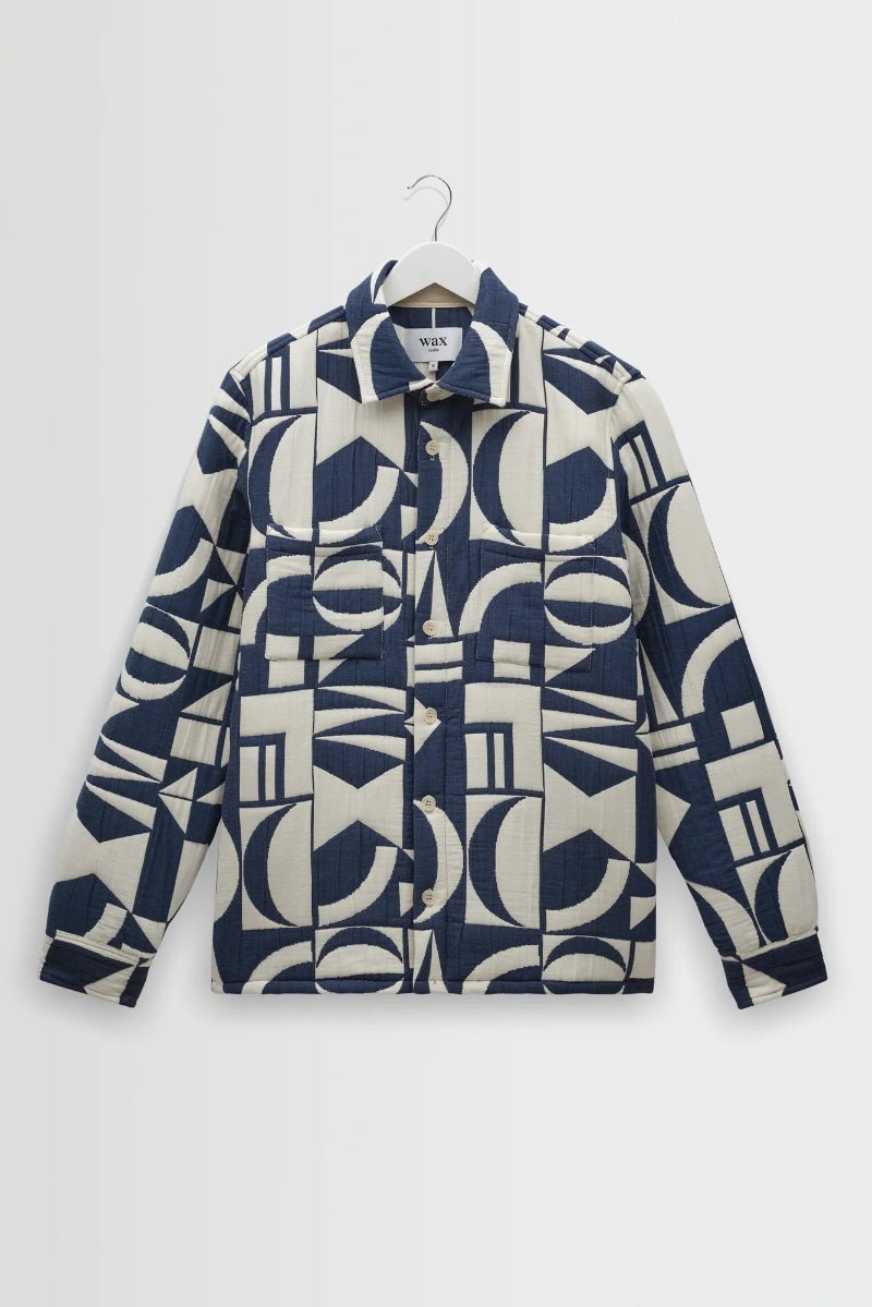 Navy and white patterned jacket on a hanger against a light gray background