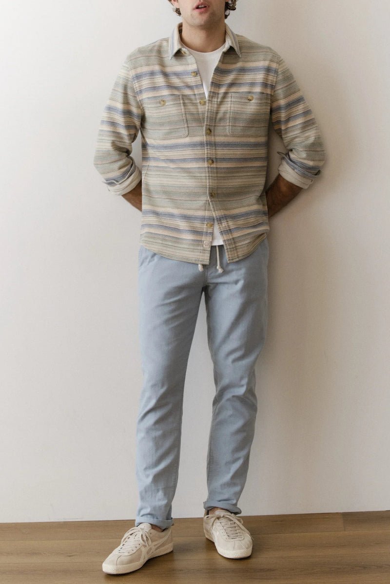 Person wearing a plaid shirt, light blue jeans, and white sneakers against a plain background