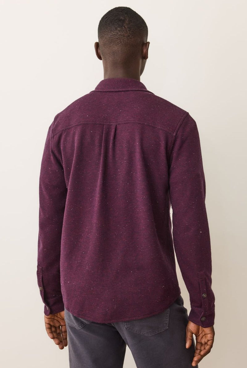 Person wearing a maroon shirt from behind on a plain background