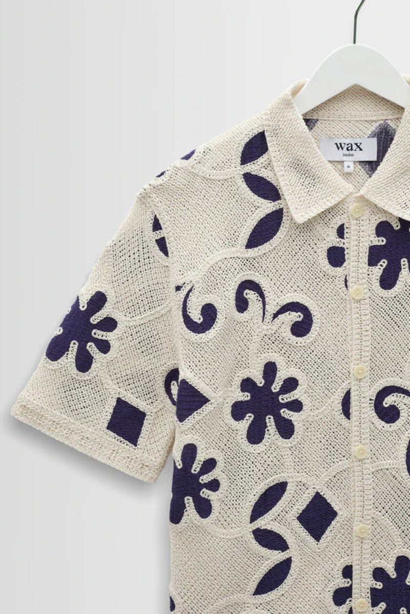 Short-sleeve shirt with floral pattern on a hanger against a white background