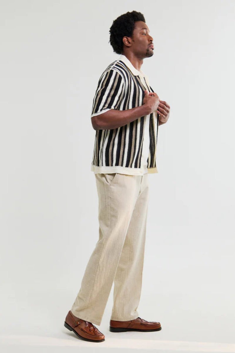 Man wearing a striped shirt and beige pants on a white background