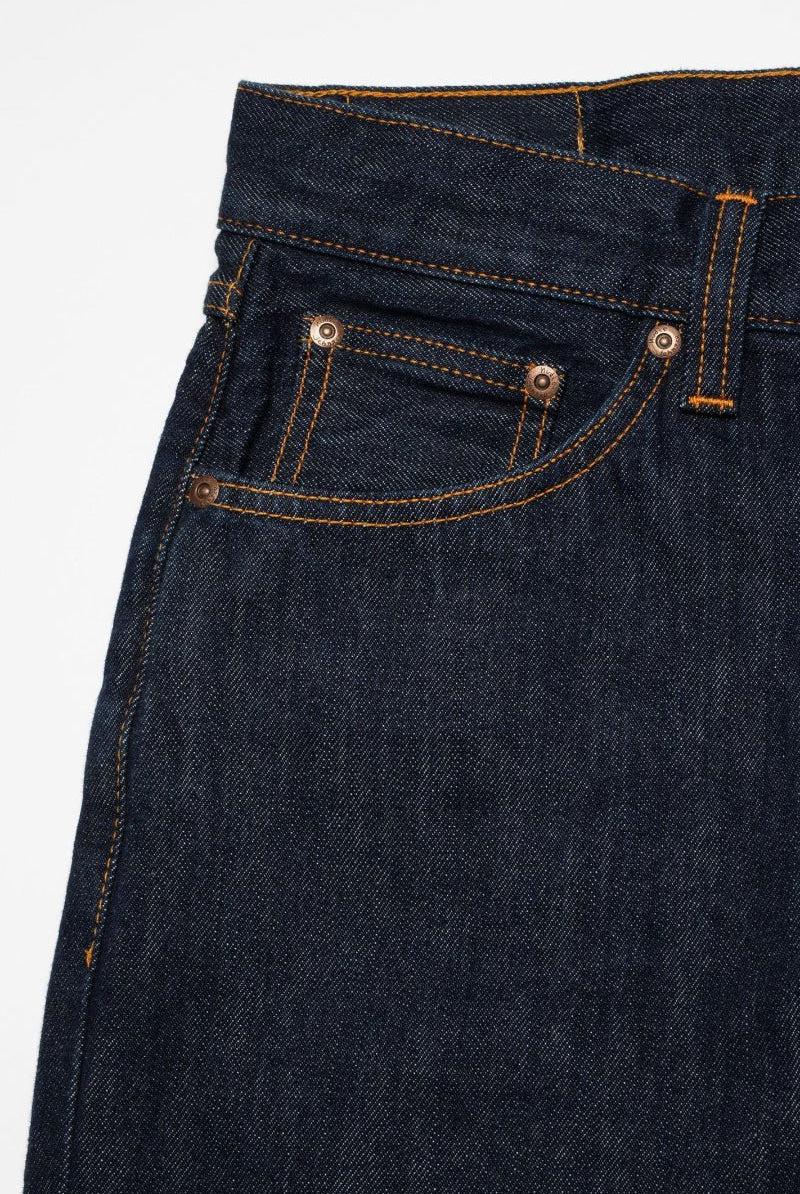 Close-up of dark blue denim jeans with stitching details on a white background
