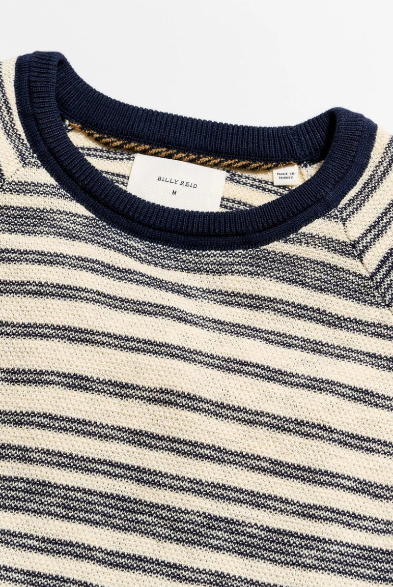 Close-up of a striped sweater with a visible brand label on a white background