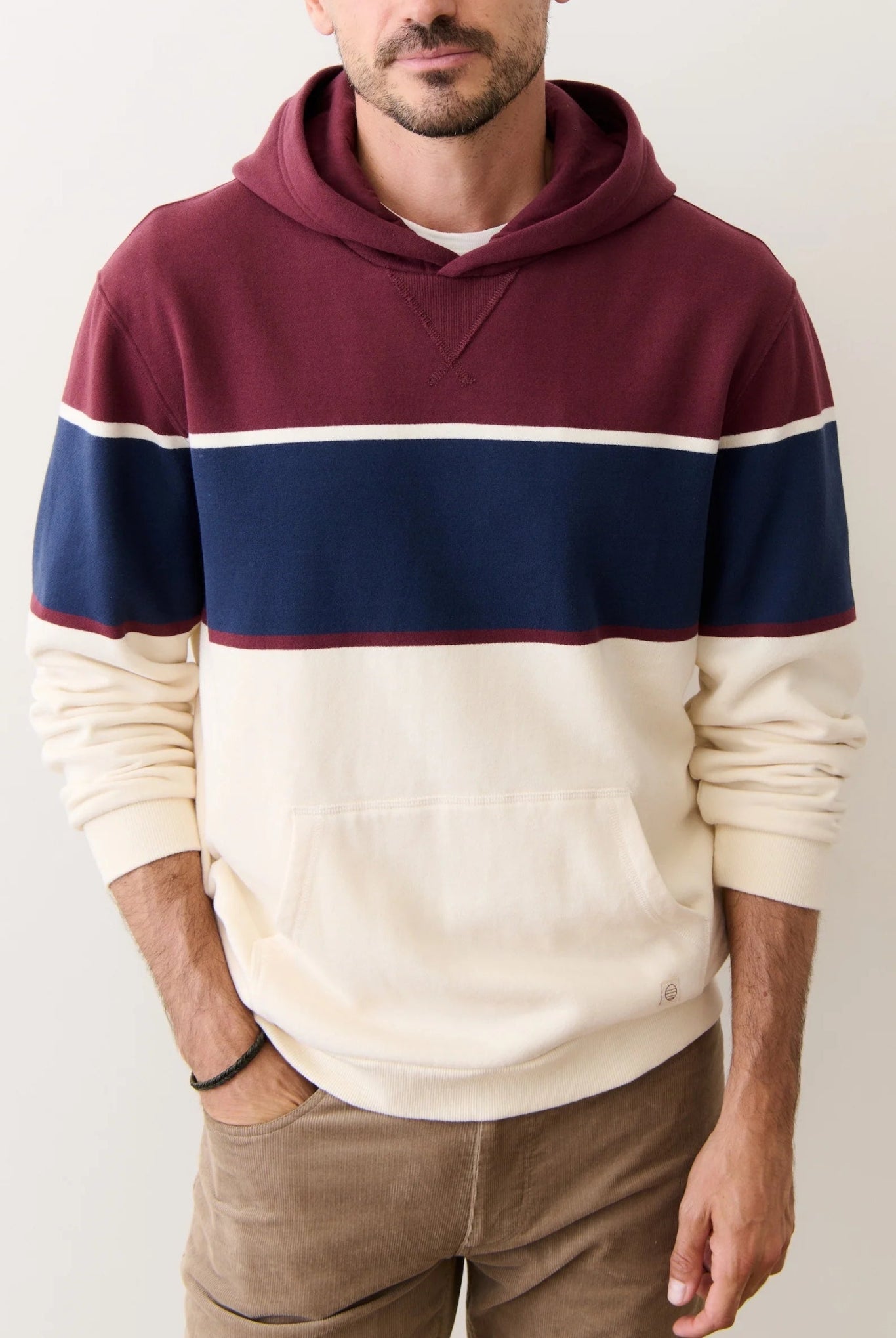 Person wearing a maroon, navy, and beige striped hoodie against a plain background