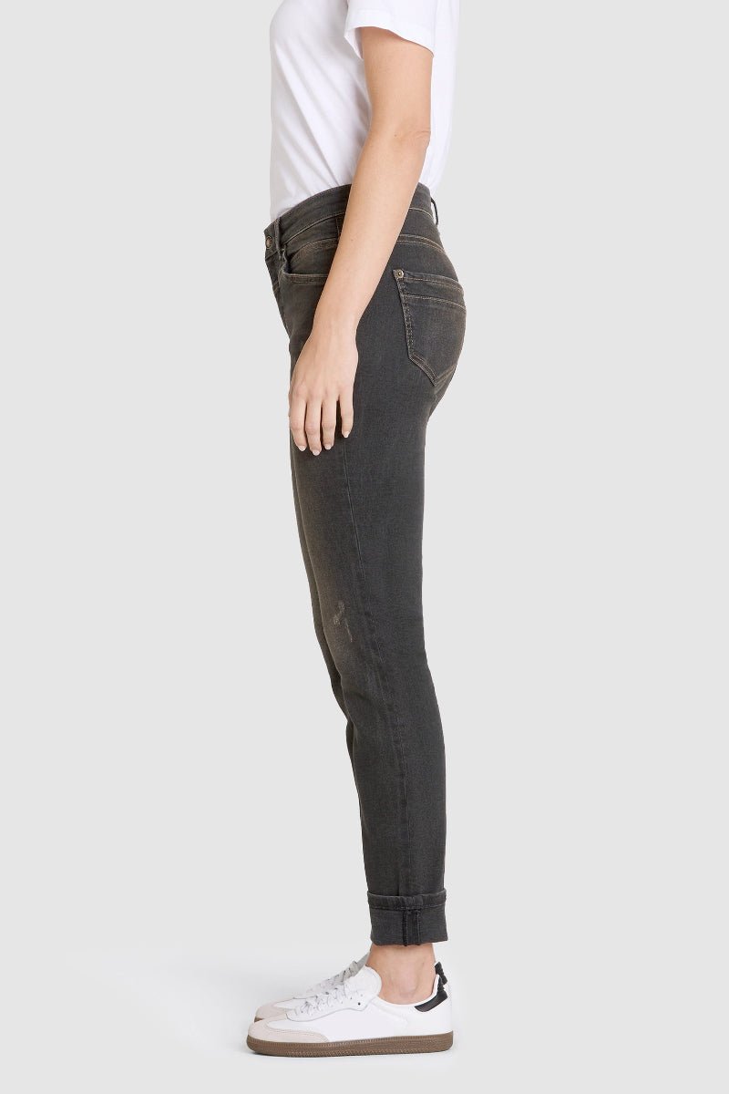 Person wearing dark jeans and white sneakers on a light gray background