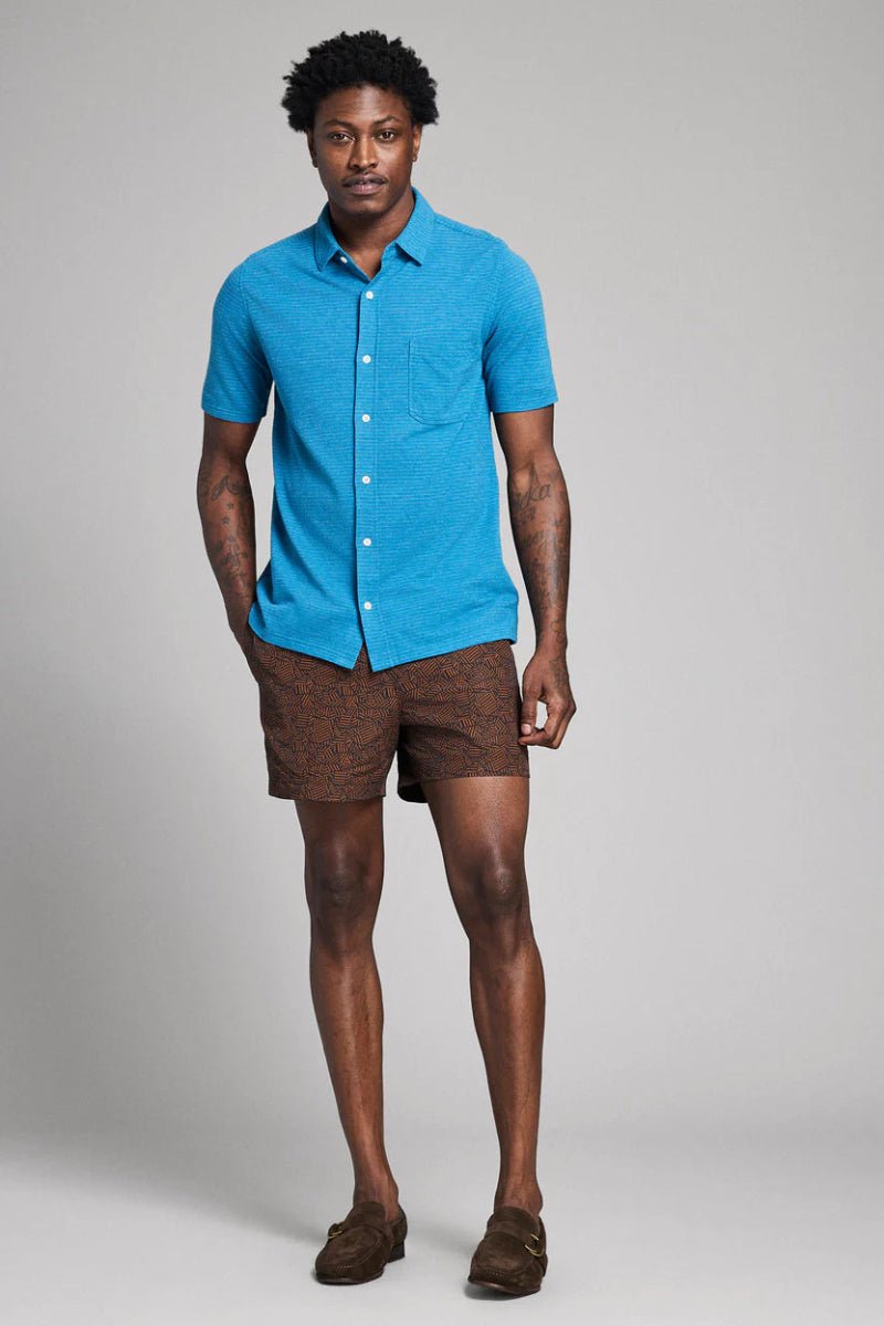 Man wearing a blue shirt and brown shorts on a gray background