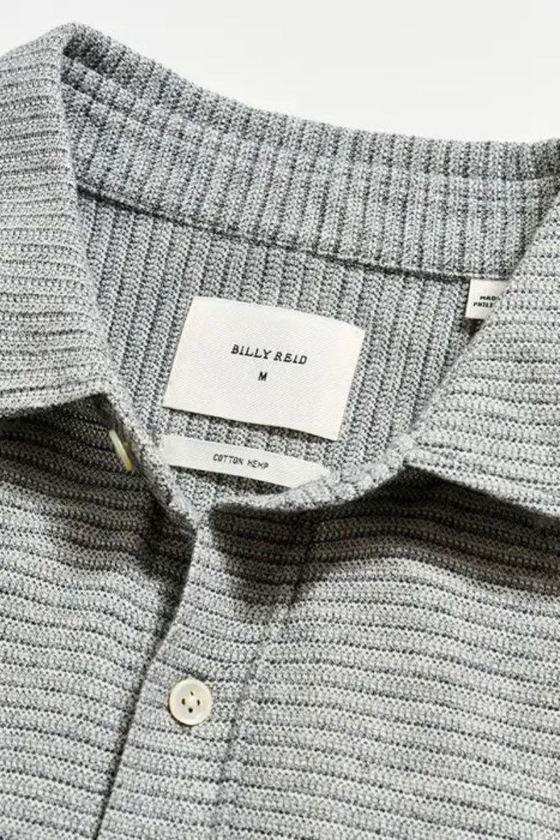 Close-up of a gray textured shirt with a brand label on a light gray background