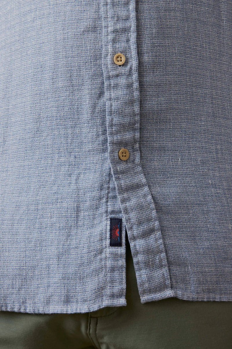 Close-up of a buttoned shirt with a brand logo on a plain background