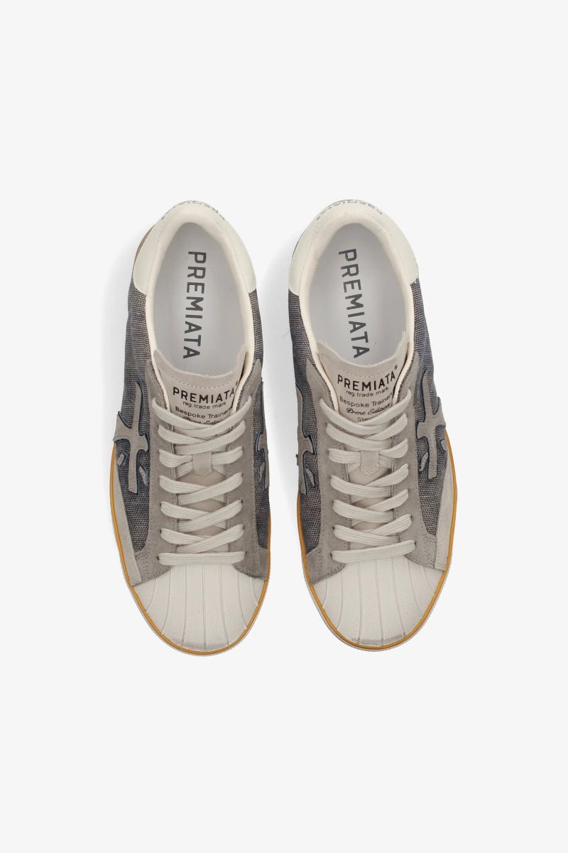 Pair of gray and white sneakers with 'Premiata' branding on a white background