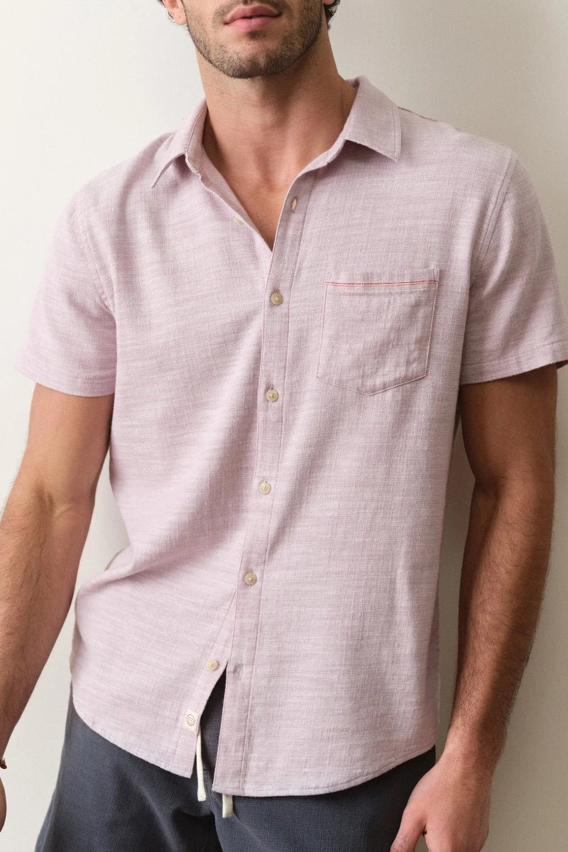 Man wearing a light pink short-sleeve shirt against a neutral background