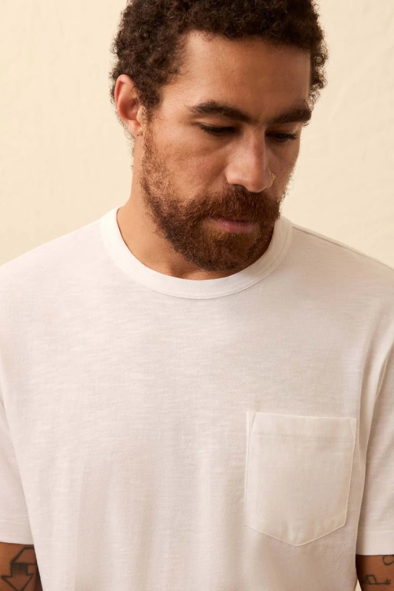 Man wearing a plain white t-shirt against a beige background