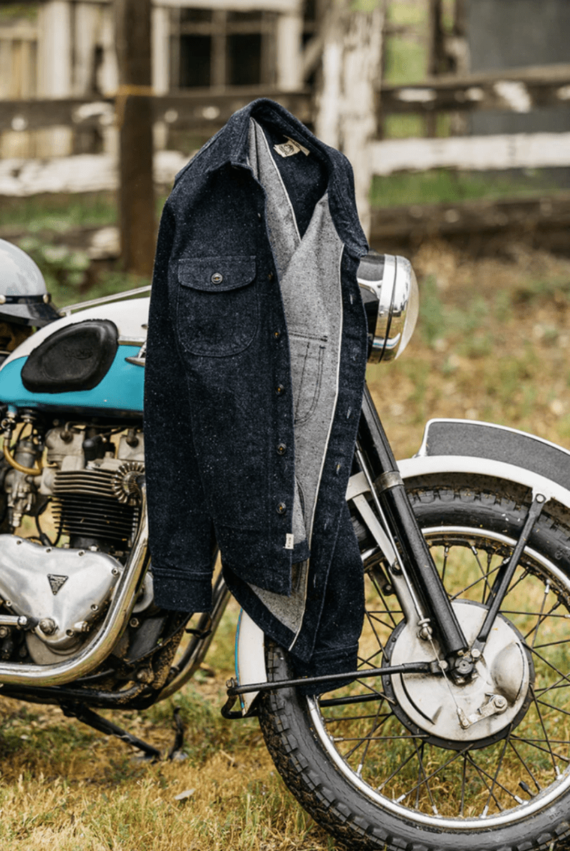 Denim jacket draped over a vintage motorcycle in an outdoor setting