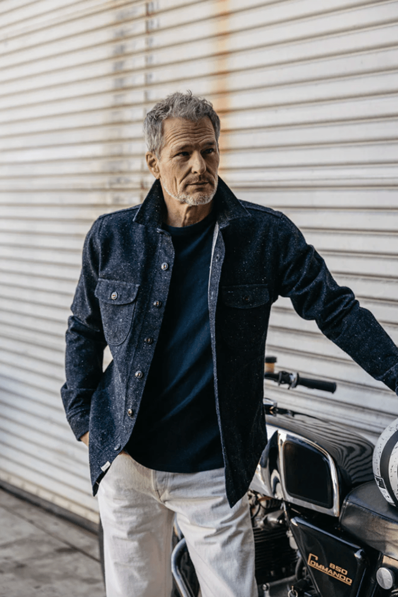 Man standing next to a motorcycle with a neutral background