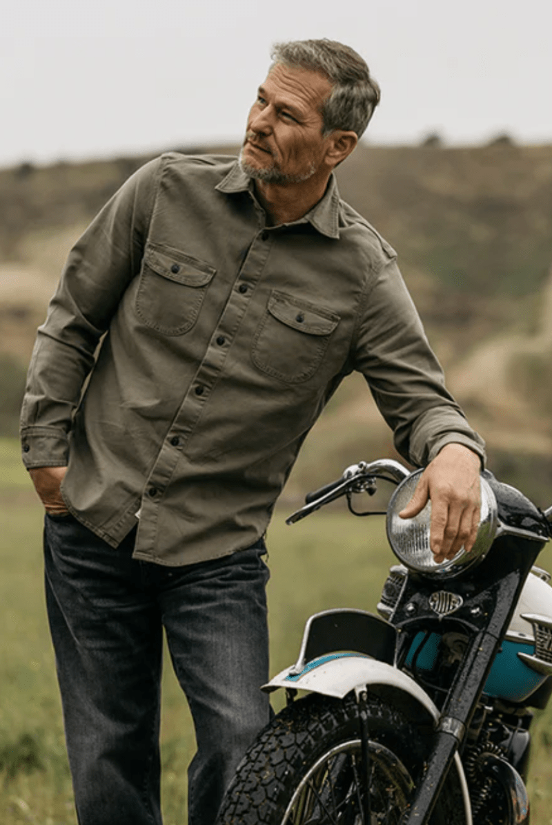 Man standing next to a motorcycle in a natural setting
