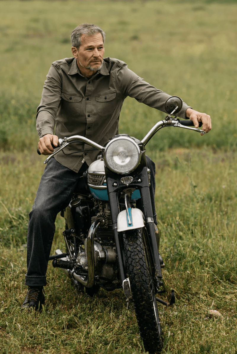Man sitting on a motorcycle in a grassy field