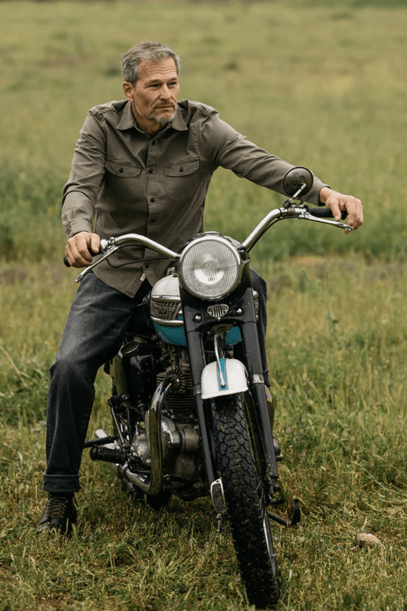 Man sitting on a motorcycle in a grassy field