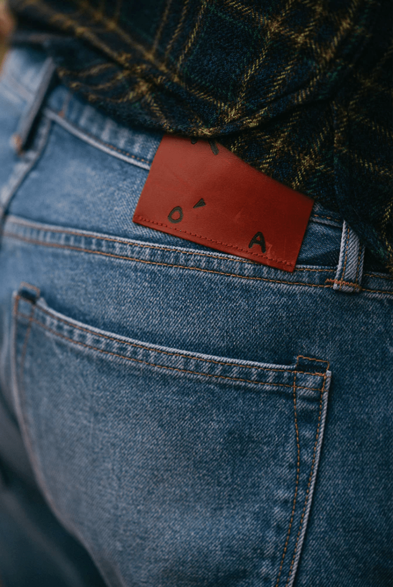 Close-up of blue jeans with a brown leather patch featuring a logo.