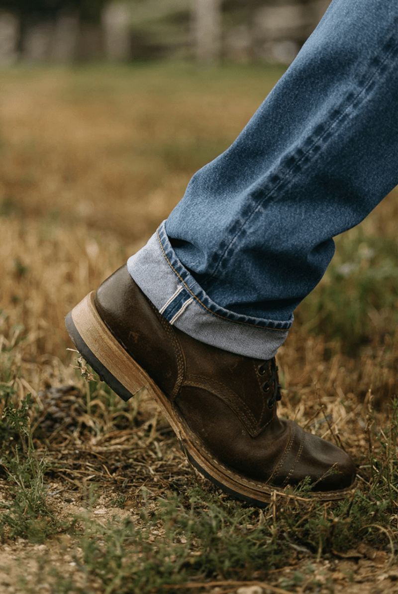 Brown leather boot on a grassy ground
