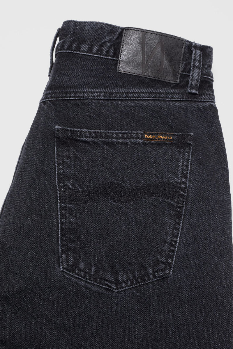 Black denim jeans with a brand logo on the back pocket against a light gray background