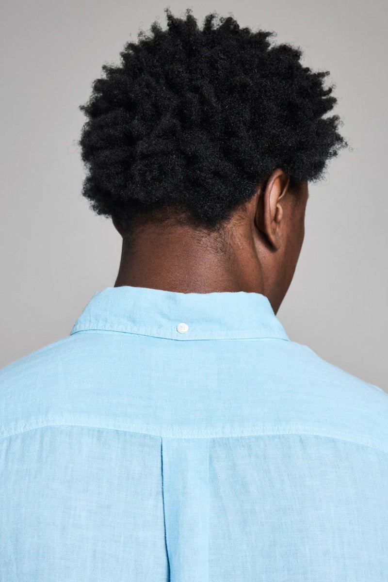 Person wearing a light blue shirt with a neutral background