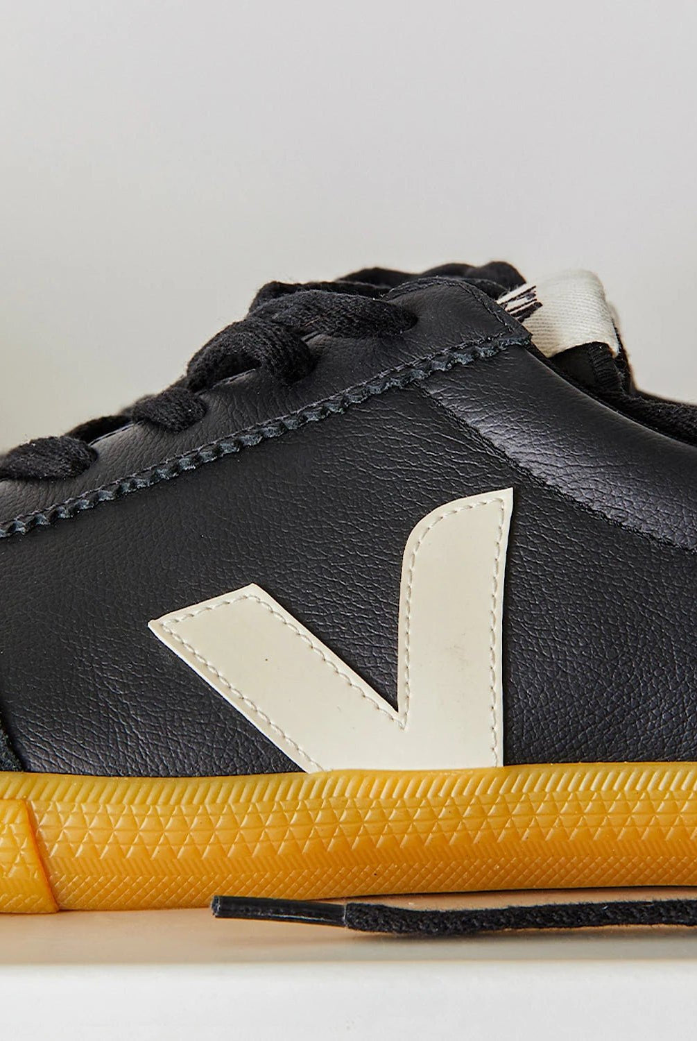 Black sneaker with yellow sole on a light gray background