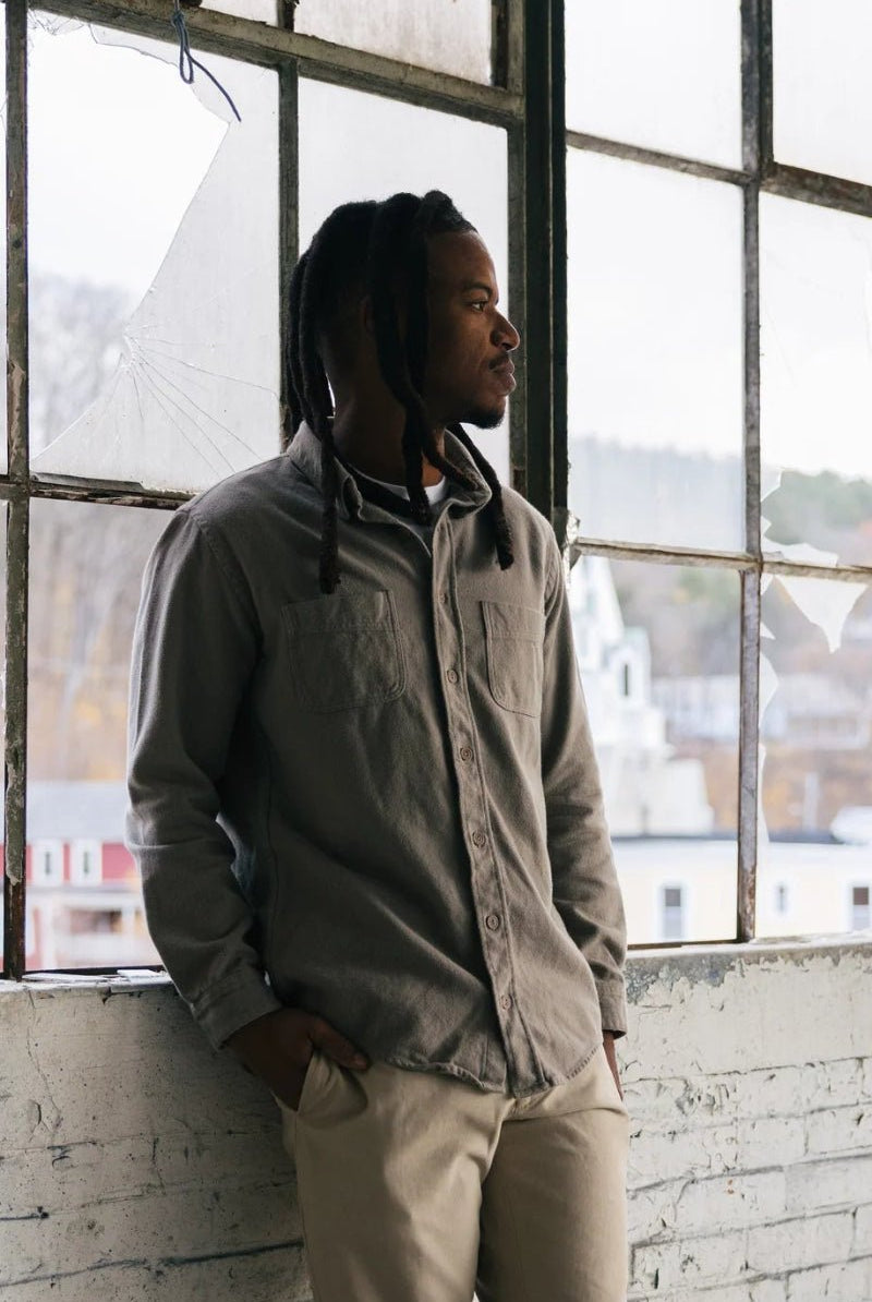 Man standing in a room with large windows, looking out.