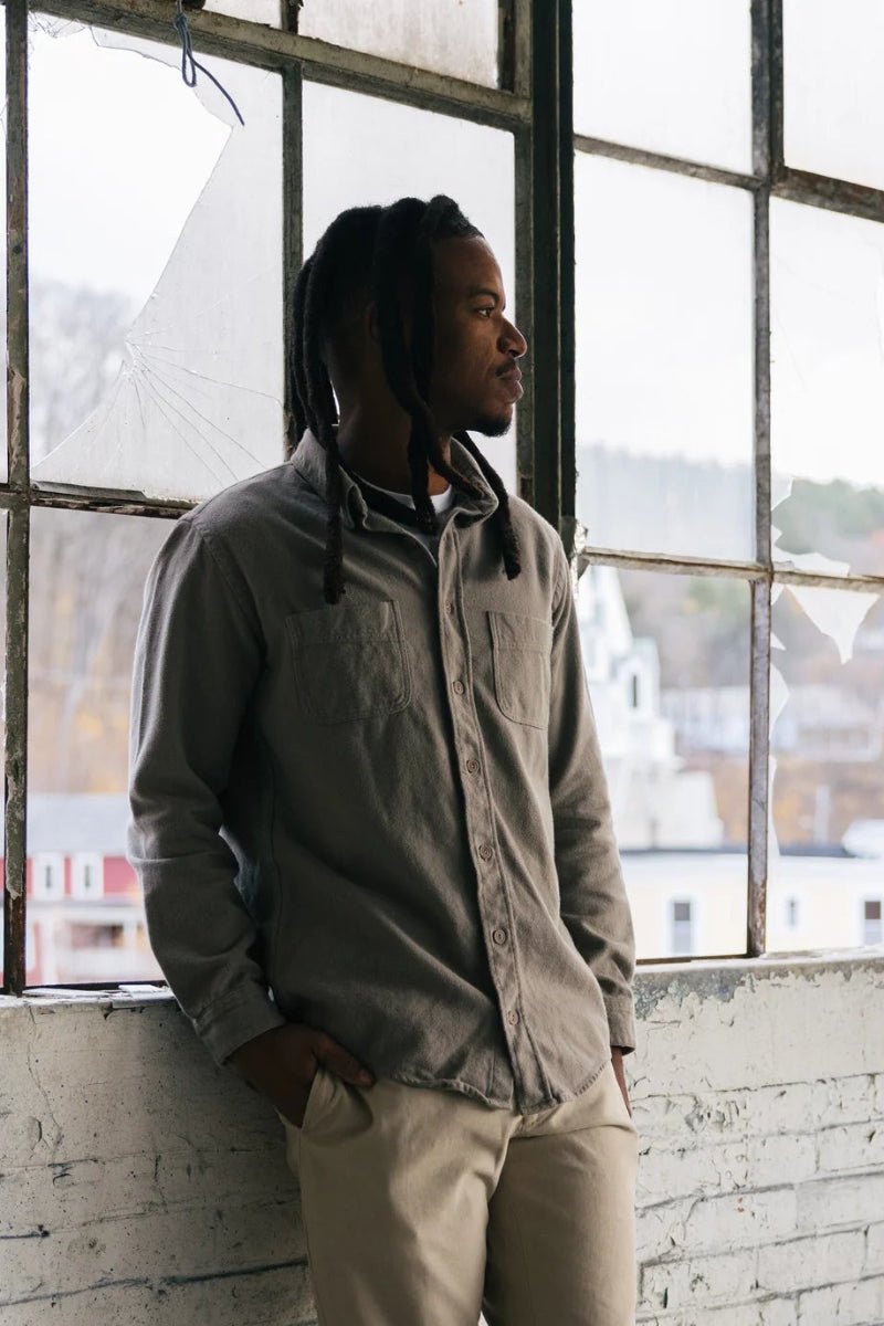 Man standing in a room with large windows, looking out.