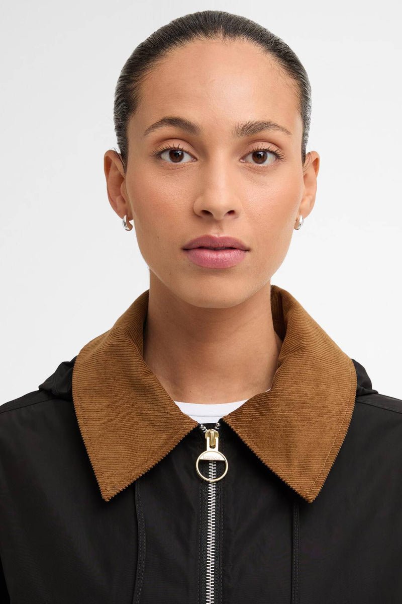 Person wearing a black jacket with a brown collar against a white background