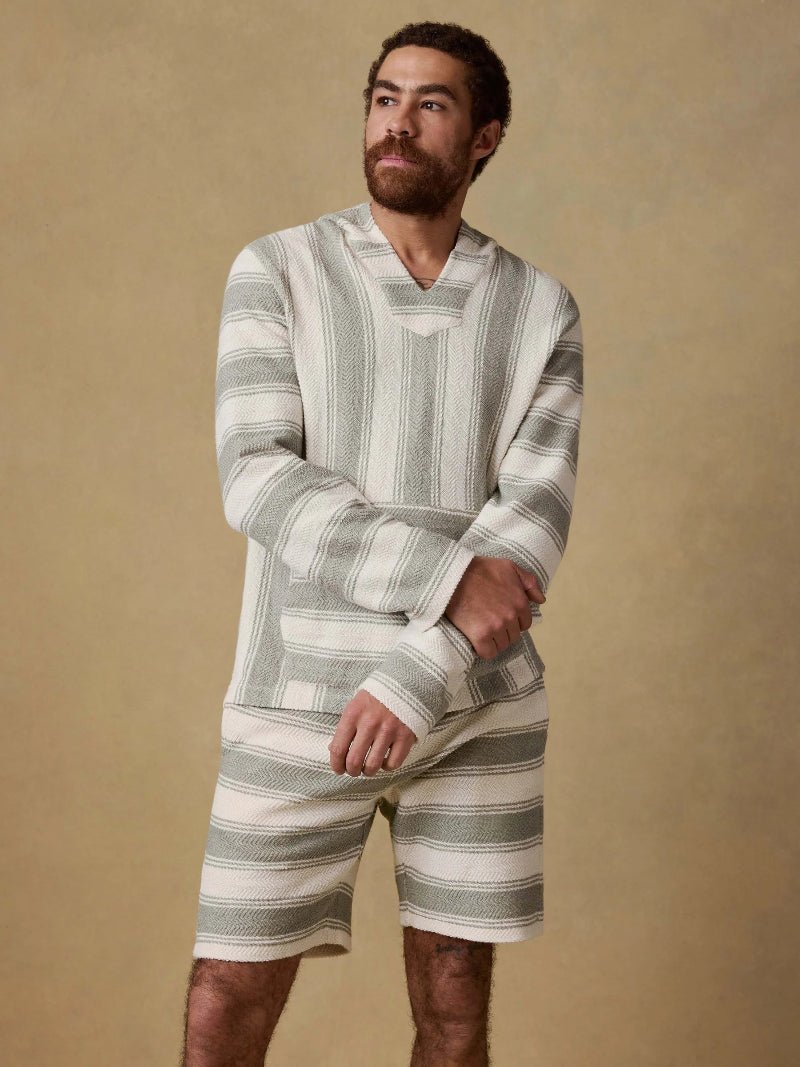 Man wearing a striped shirt and shorts against a beige background