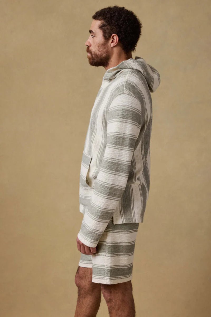 Man wearing a striped hoodie and shorts on a beige background