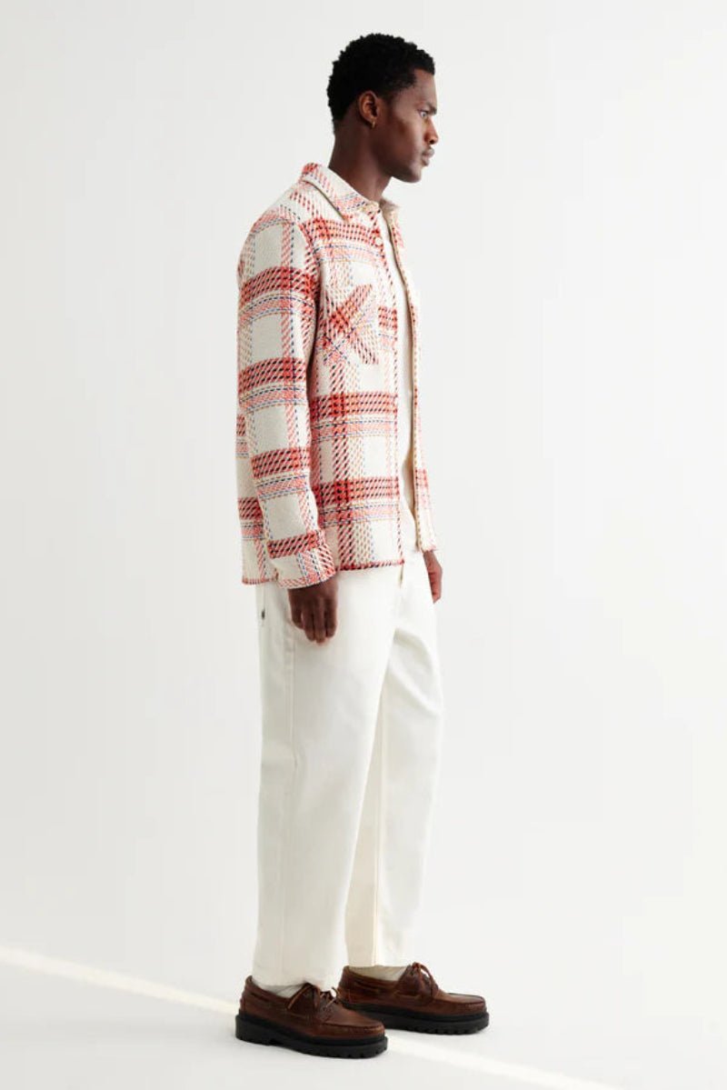 Man wearing a plaid shirt and white pants on a white background