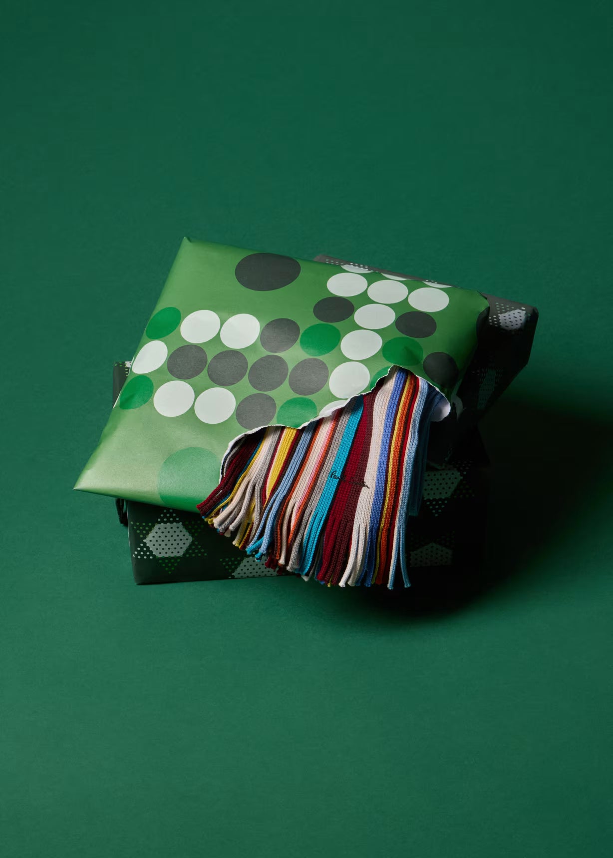 Green fabric bag with colorful tassel on a green background