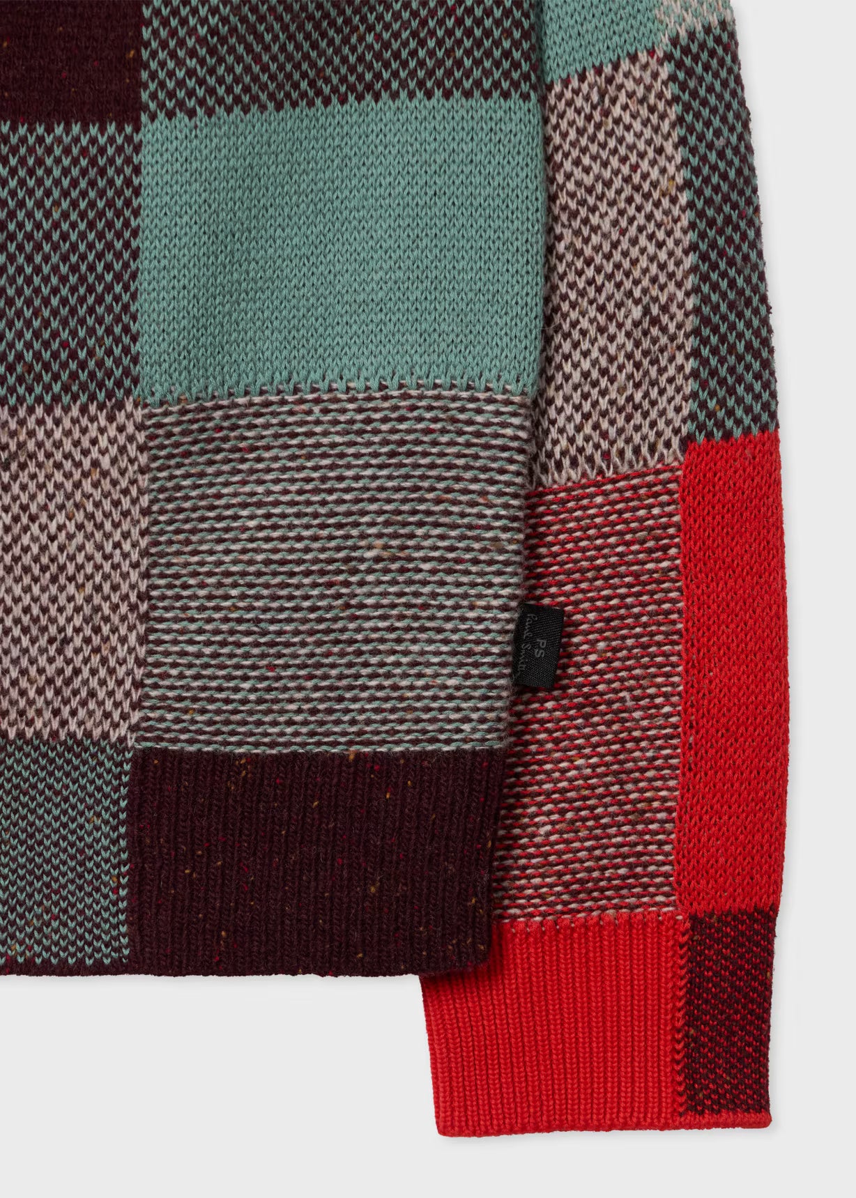 Close-up of a plaid fabric with red, green, and brown colors on a white background.