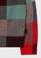 Close-up of a plaid fabric with red, green, and brown colors on a white background.