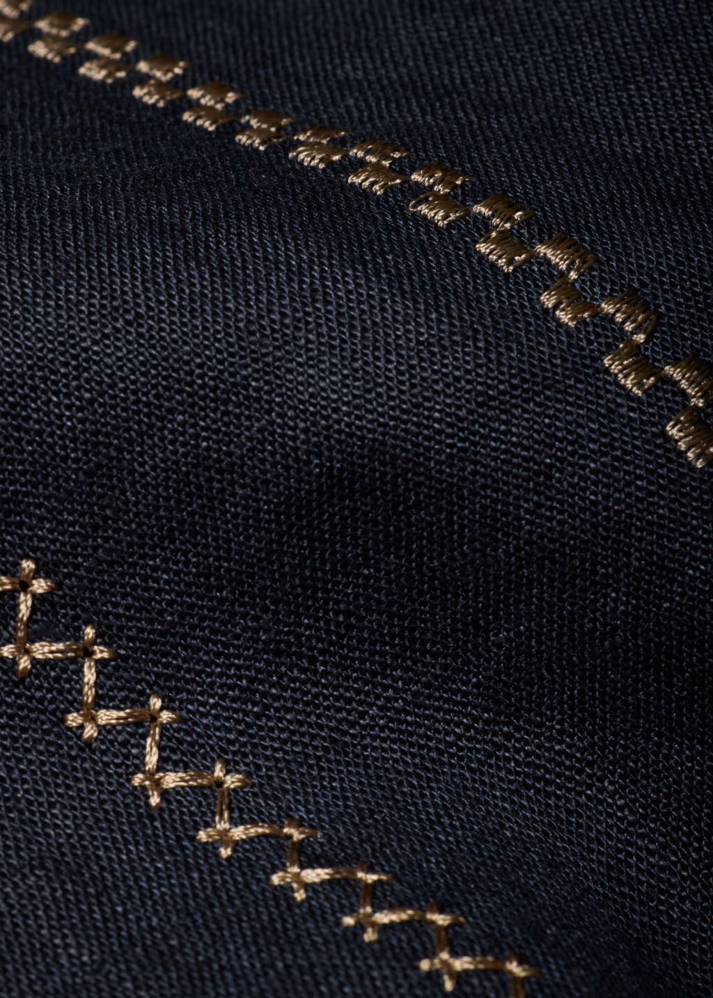 Close-up of black fabric with gold embroidery on a dark background