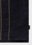 Black fabric with gold stitching on a white background