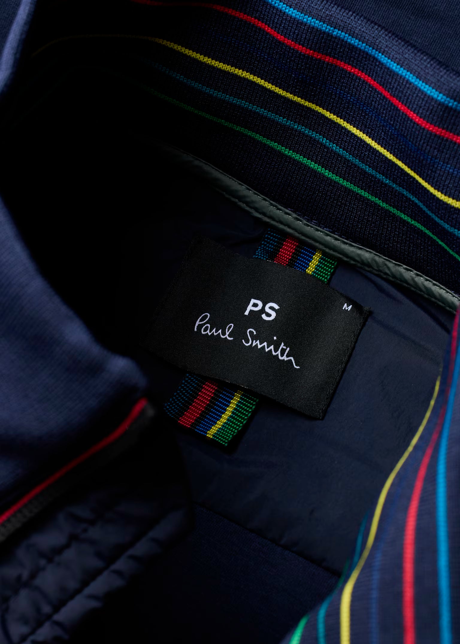 Close-up of a Paul Smith label on a garment with colorful stripes.