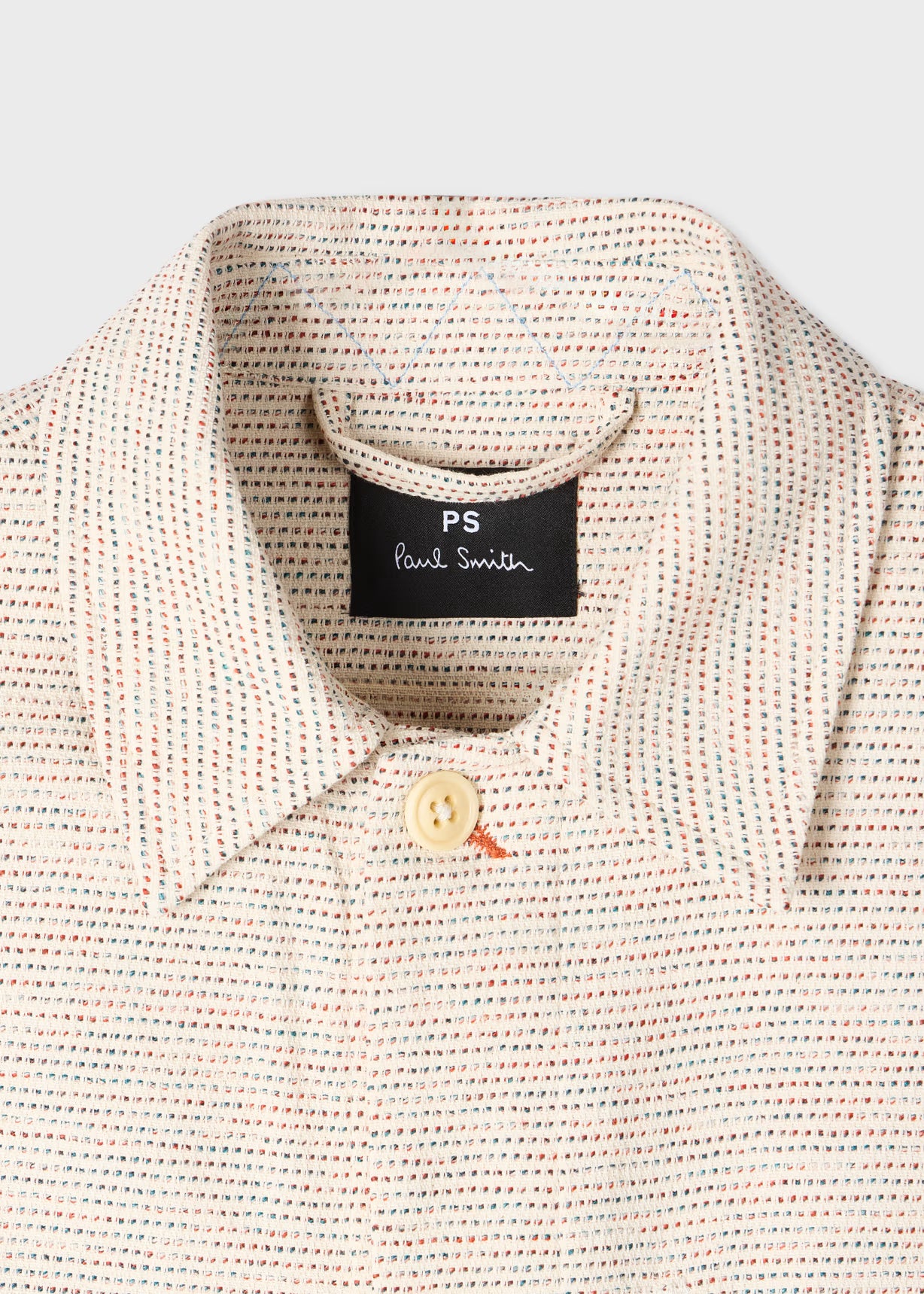 Close-up of a textured shirt with a Paul Smith label on a light gray background