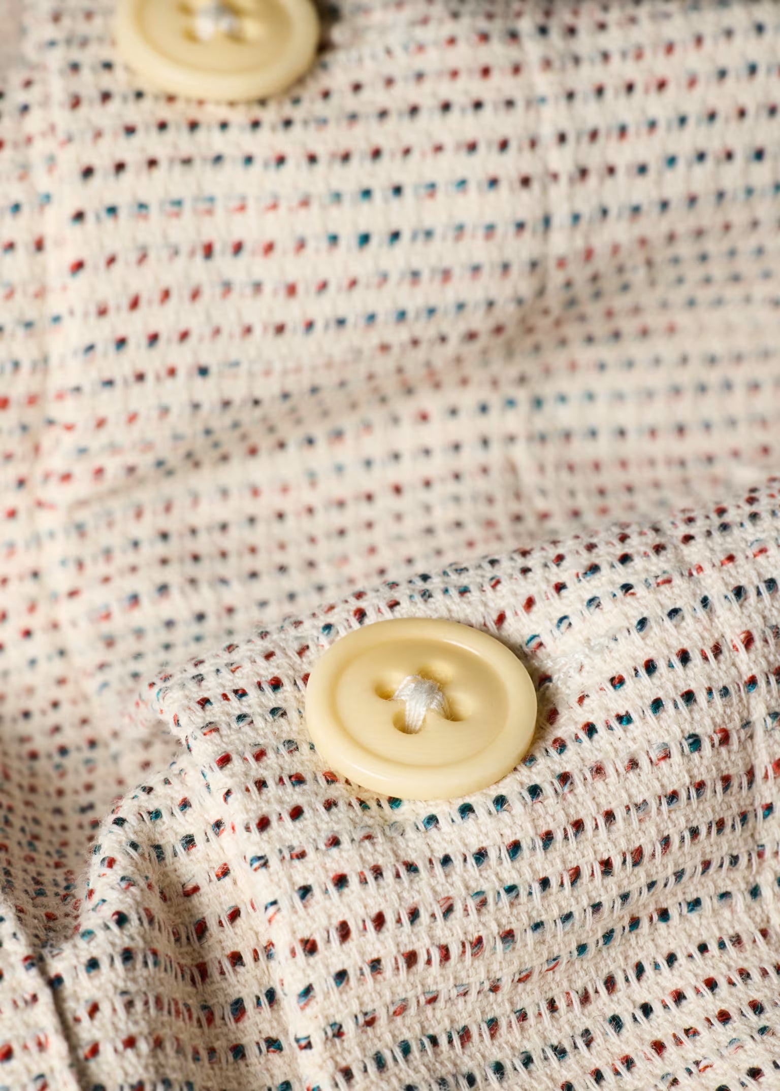 Close-up of a textured fabric with a button on a multicolored background